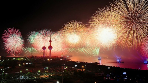 A vibrant display of fireworks illuminating the night sky over Kuwait City.