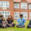 Pupils from The King's School Ottery sitting outside on the grass