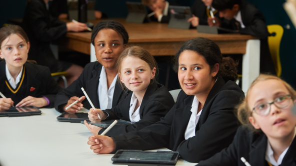 Caterham School pupils sit at table with their iPads