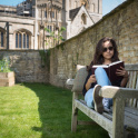 Exterior view of Burford School, showcasing historic architecture, well-maintained school grounds with a teenage girl on bench studying.
