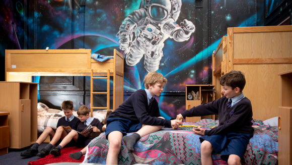 Boarder at Cheam School play games and read on beds in the dormitory