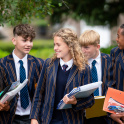 Colston's School pupils in uniform holding folders, books and stationary.
