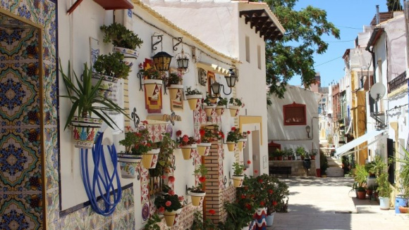 Street view in the Santa Cruz neighbourhood of Costa Blanca, featuring colourful houses, vibrant architectural details and hanging plant pots.