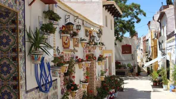 Street view in the Santa Cruz neighbourhood of Costa Blanca, featuring colourful houses, vibrant architectural details and hanging plant pots.