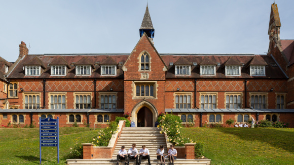 Pupils sitting in front of the main building at Cranleigh School