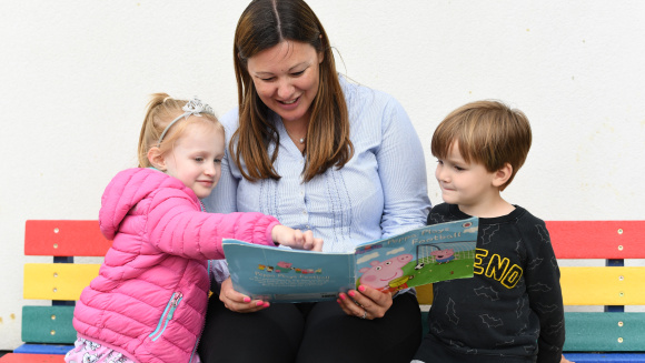 Pupils and teacher reading together at Eaton House the Manor Nursery