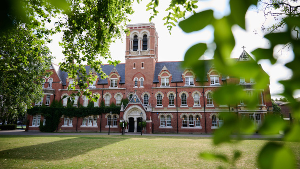 A view, framed by tree leaves of the main building of Emanuel School