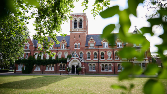 A view, framed by tree leaves of the main building of Emanuel School
