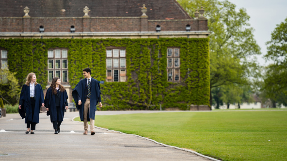 Pupils at Felsted School wearing gowns walk along school drive