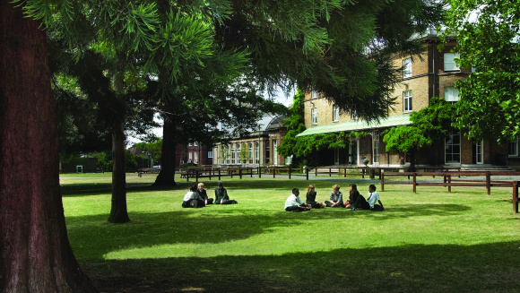 Summer time at the Graveney School in Tooting and pupils are sitting on the grass during break.