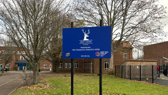 The school sign of Grey Coat School in Ham with the school buildings in the background