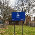 The school sign of Grey Coat School in Ham with the school buildings in the background