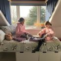 Two girl boarders at Hall Grove School sit on a bed in the boarding house