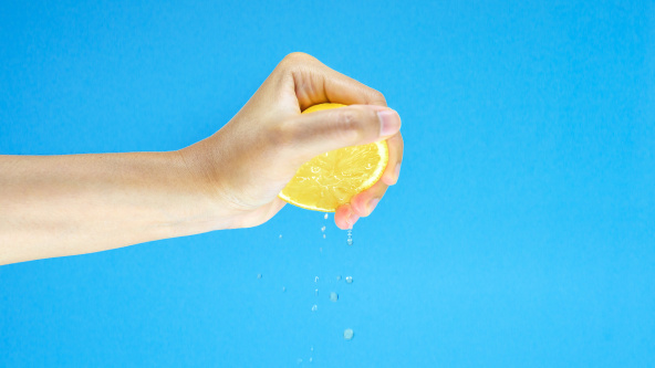 A woman's hand squeezing juice from a lemon