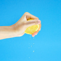 A woman's hand squeezing juice from a lemon