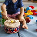 Nursery school child plays with drum surrounded by other toys