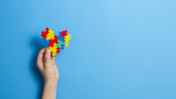 A hand holding a heart made of jigsaw pieces