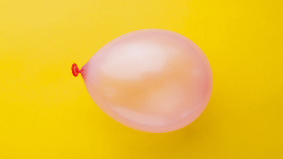A pink balloon on a yellow background
