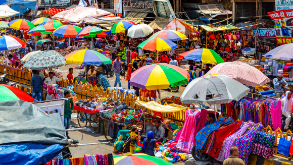 Busy, crowded street in old Delhi, India. People selling different products on streets under brightly coloured umbrellas