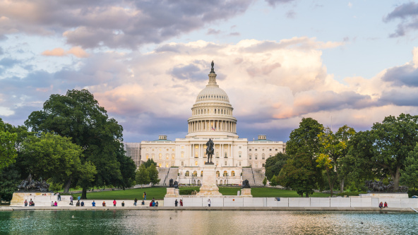 The United States Capitol building at sunset with reflection in water.