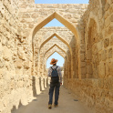 Man Walking Along the Iconic Archways in Bahrain Fort, Manama, Bahrain