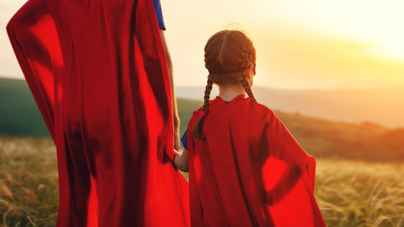 A parent and child in superhero capes
