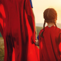 A parent and child in superhero capes