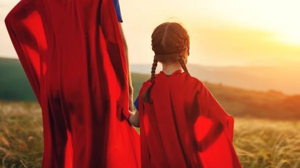 A parent and child in superhero capes