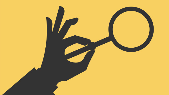A hand holding a magnifying glass