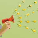 A child holding a handheld megaphone with yellow roses heads spread out in the air.