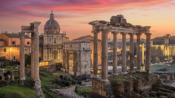 Rome, Italy at the historic Roman Forum ruins at dusk.
