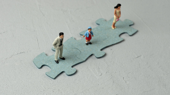 A family of minitures standing on jigsaw puzzle pieces