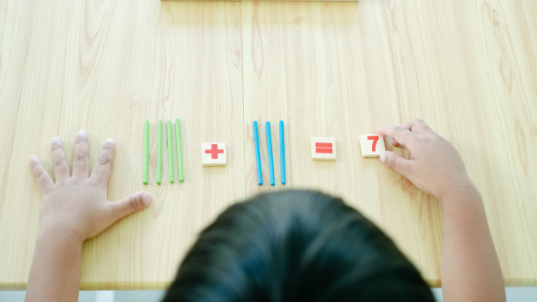 An illustration of a child learning to count with coloured sticks