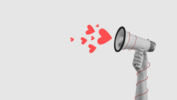 A hand holding a megaphone that's shooting hearts