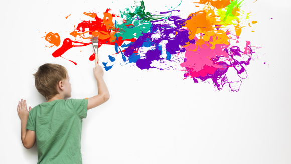 A child painting something colourful on a white wall