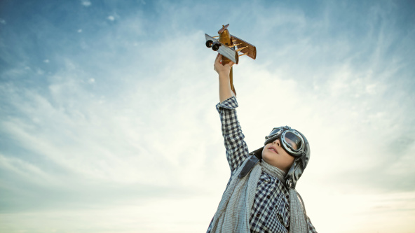 A child dressed as a pilot flying a toy aeroplane