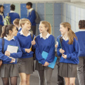 Girls in school blue school uniform walk along secondary school corridor