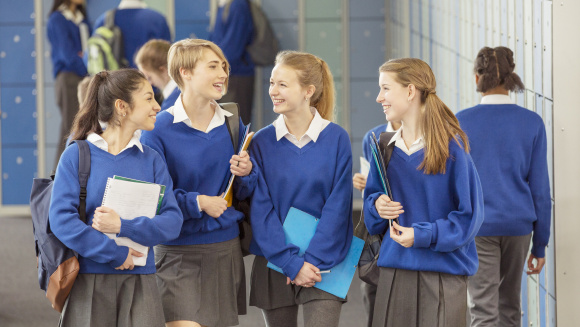 Girls in school blue school uniform walk along secondary school corridor