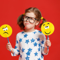 A child holding two paddles, one with a sad face and another with a happy face
