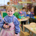 A child in art smock and princess dress at King&rsquo;s House nursery