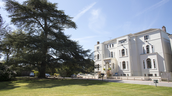 Exterior of Lambrook School of white building in sunny green scenery. Independent school.