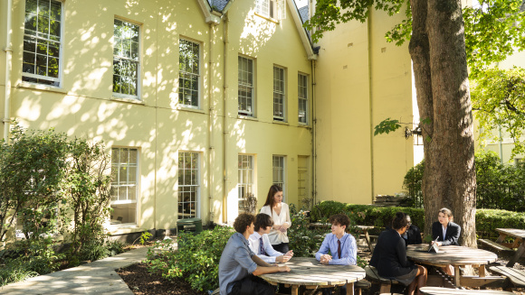 North Bridge House students working at picnic tables outside under the shade of a tree