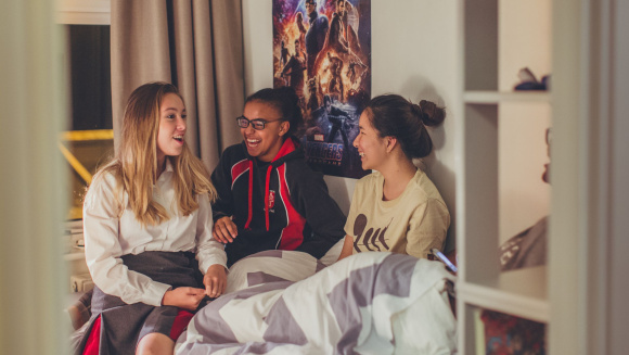 Boarding pupils at New Hall School sit on a dormitory bed