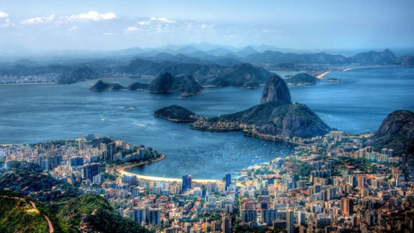 View of Rio de Janeiro, showcasing the city skyline surrounded by iconic rocky landscapes under a clear sky.