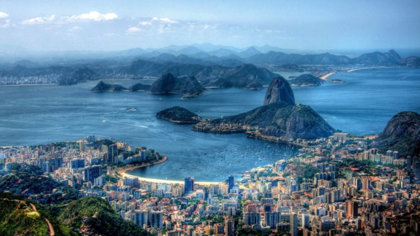 View of Rio de Janeiro, showcasing the city skyline surrounded by iconic rocky landscapes under a clear sky.