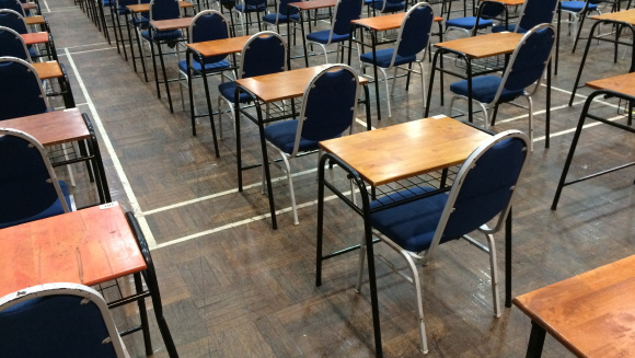 An exam hall at a school with individual tables and blue chairs