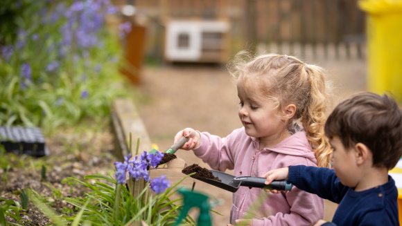 Two nursery children are gardening in a raised bed, at St Andrew's Prep, Eastbourne