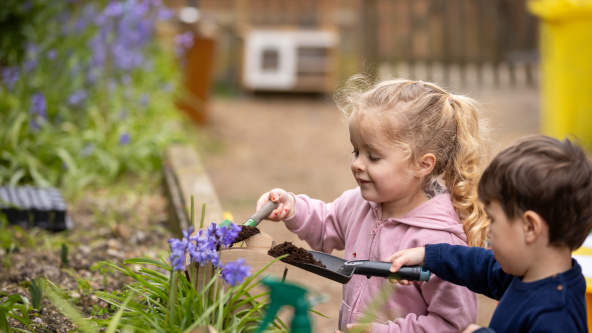 Two nursery children are gardening in a raised bed, at St Andrew's Prep, Eastbourne