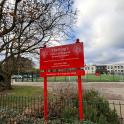 The school sign of The King&rsquo;s Church of England Primary School, with the school buildings and astroturf in the background