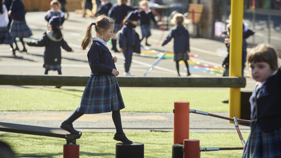 A girl in uniform walks across playground apparatus at The Study Prep, Wimbledon